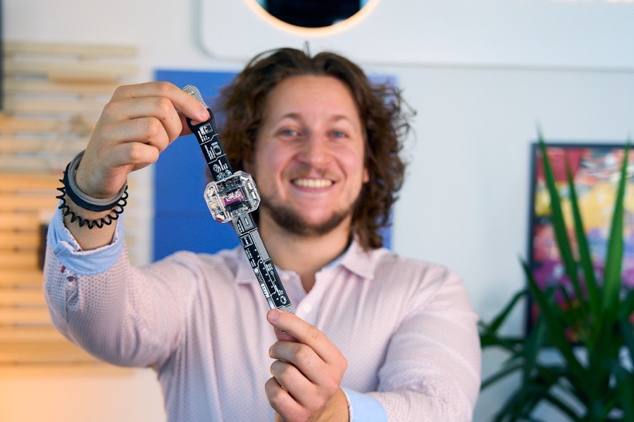 Albert Gajšak holding a buildable smartwatch dangling by its circuit-board strap.