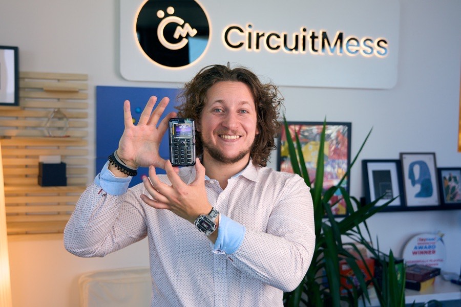 Albert Gajšak holding up a MAKERphone with both hands beneath the CircuitMess logo.