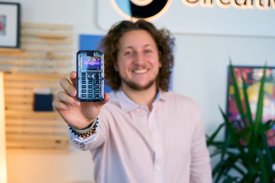 Albert Gajšak holding a clear-cased MAKERphone out towards the camera, smiling.