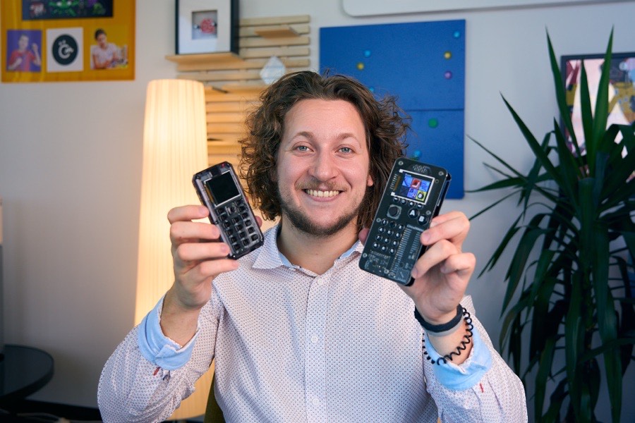 Albert Gajšak holding up two MAKERphone units, one in a black case and one in a clear case.